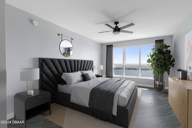 bedroom with ceiling fan, a water view, and dark hardwood / wood-style flooring