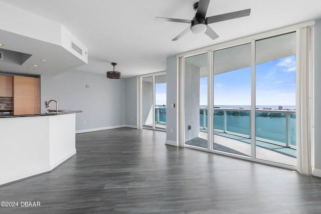 unfurnished living room with dark wood-type flooring, a water view, and floor to ceiling windows