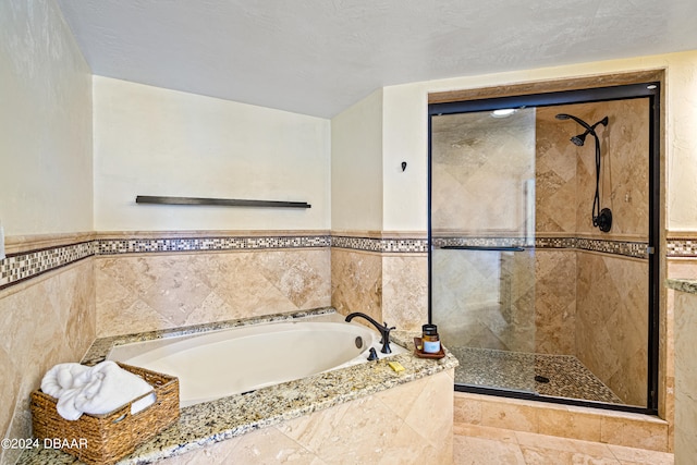 bathroom with shower with separate bathtub and a textured ceiling