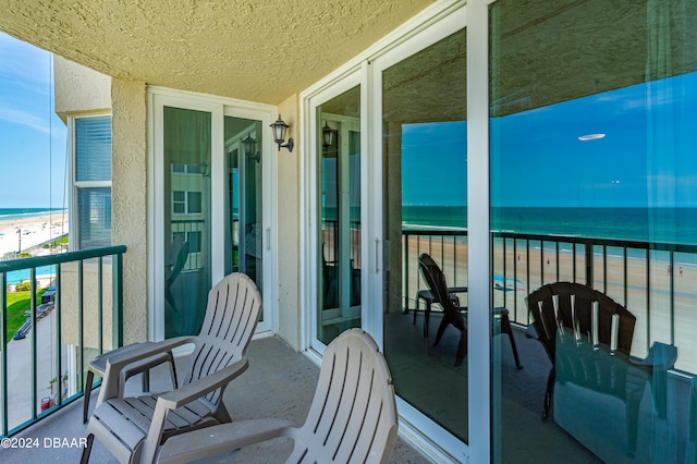 balcony featuring a beach view and a water view