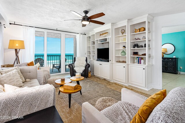 living room featuring a textured ceiling, light tile patterned floors, and ceiling fan