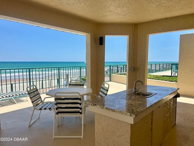 view of patio featuring a water view, sink, and a balcony