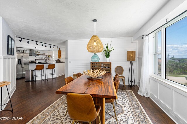 dining area with rail lighting, plenty of natural light, and dark wood-type flooring