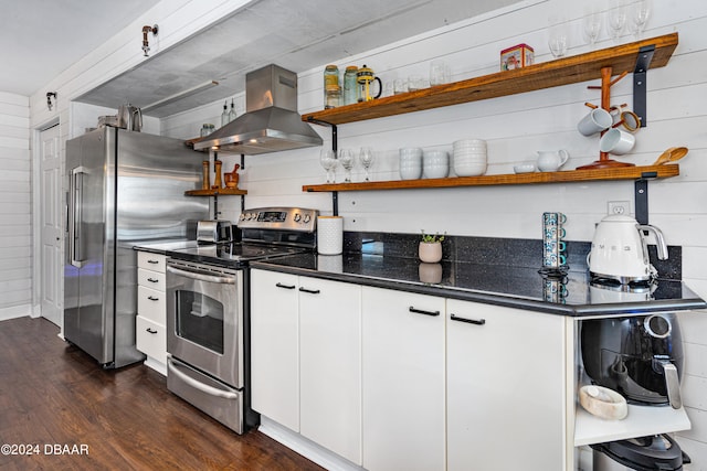 kitchen with ventilation hood, white cabinetry, appliances with stainless steel finishes, wooden walls, and dark wood-type flooring