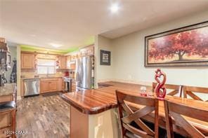 kitchen with light brown cabinets, dark hardwood / wood-style flooring, kitchen peninsula, and stainless steel appliances