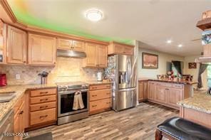 kitchen featuring light brown cabinets, ceiling fan, light wood-type flooring, appliances with stainless steel finishes, and tasteful backsplash