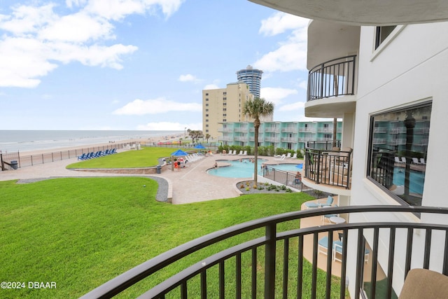 view of pool featuring a patio, a water view, and a lawn