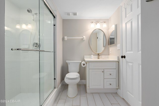 bathroom with toilet, an enclosed shower, vanity, and tile patterned floors