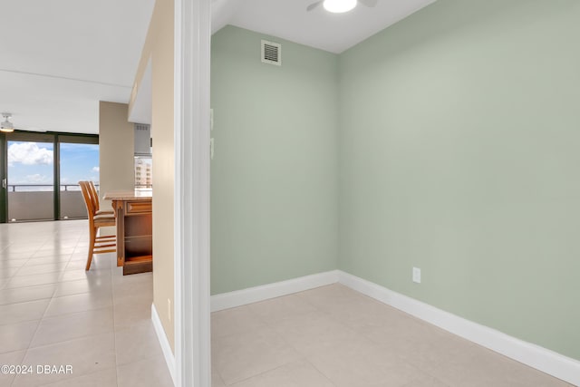 empty room featuring expansive windows, light tile patterned floors, and ceiling fan