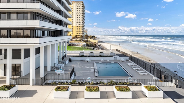 exterior space with a beach view, a water view, and a community pool