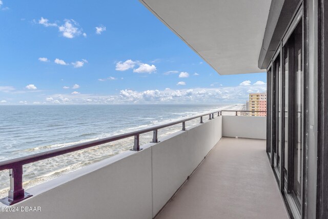 balcony featuring a view of the beach and a water view