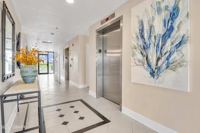 2200 N Atlantic Ave Unit 1602, Daytona Beach, FL 32118 - hallway with elevator, a textured ceiling, baseboards, and light tile patterned floors