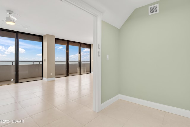 unfurnished room featuring expansive windows, lofted ceiling, light tile patterned floors, and ceiling fan