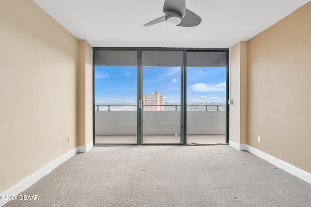 carpeted spare room featuring floor to ceiling windows and ceiling fan