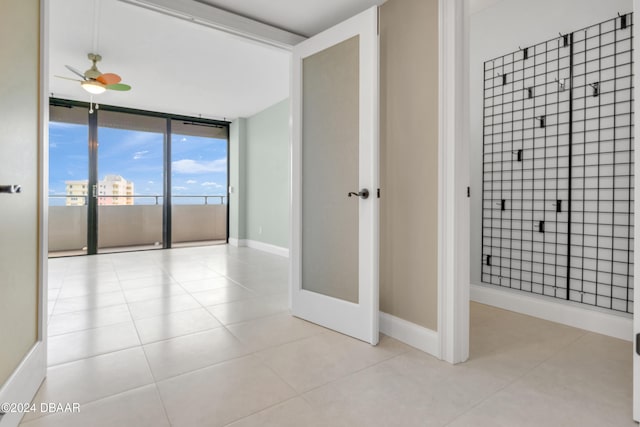 interior space with a wall of windows, tile patterned flooring, and ceiling fan