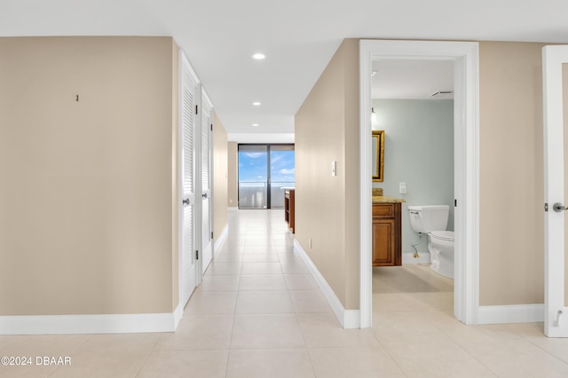 hall with a wall of windows and light tile patterned flooring