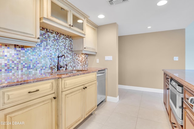 kitchen featuring light tile patterned flooring, sink, cream cabinets, appliances with stainless steel finishes, and backsplash