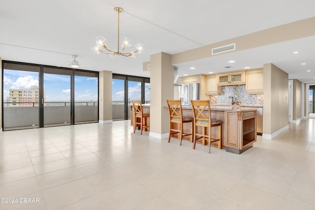 kitchen with floor to ceiling windows, ceiling fan with notable chandelier, light tile patterned floors, stainless steel fridge, and decorative backsplash