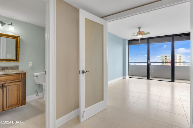 corridor with a wall of windows, light tile patterned floors, and sink