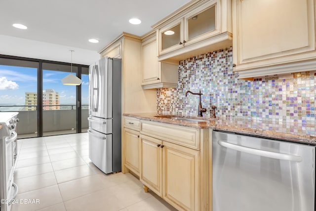 kitchen featuring stainless steel appliances, light stone counters, sink, tasteful backsplash, and decorative light fixtures