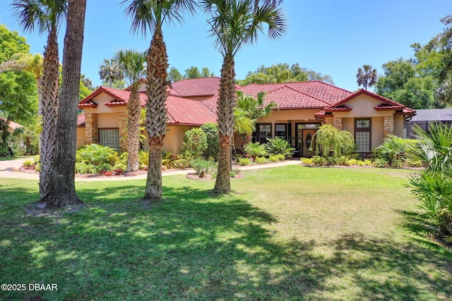 mediterranean / spanish-style house featuring stucco siding, a tiled roof, and a front lawn