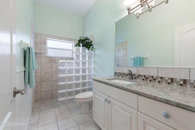 full bath featuring toilet, a walk in shower, tile patterned floors, decorative backsplash, and vanity