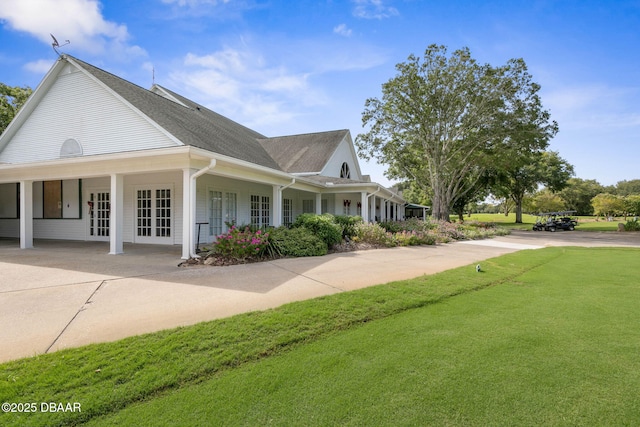 view of home's exterior with a lawn, french doors, and concrete driveway
