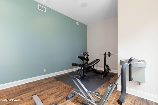 workout room featuring baseboards, visible vents, and wood finished floors