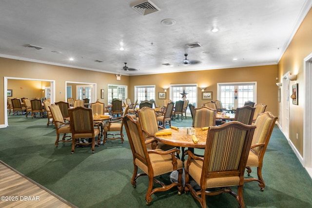 carpeted dining space featuring baseboards, crown molding, and visible vents