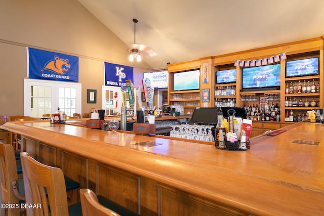 bar with ceiling fan, a bar, and high vaulted ceiling