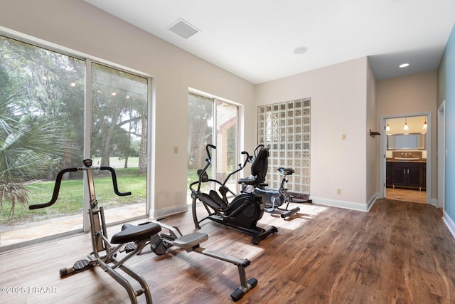 workout room with baseboards, visible vents, and wood finished floors