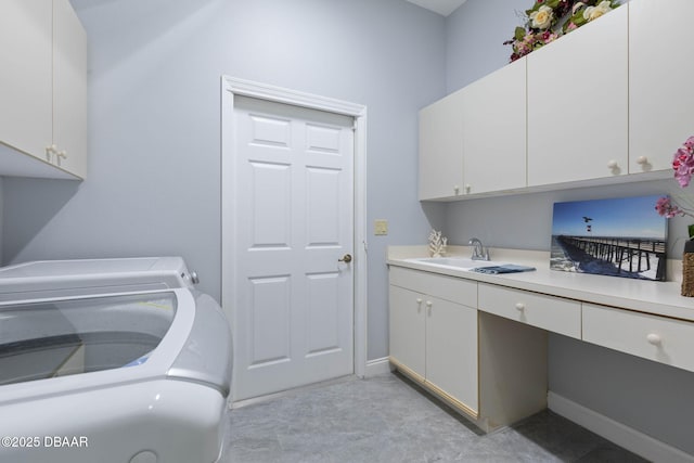 washroom with washing machine and dryer, a sink, cabinet space, and baseboards