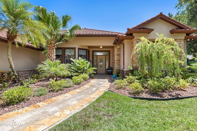 view of front of house with stone siding, a tiled roof, and stucco siding