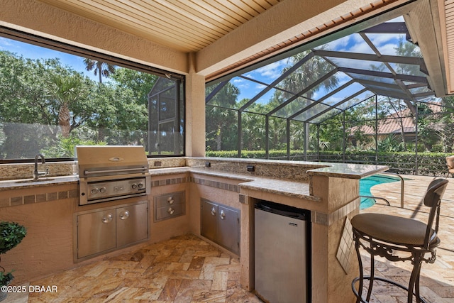view of patio with a sink, a grill, glass enclosure, an outdoor pool, and exterior kitchen