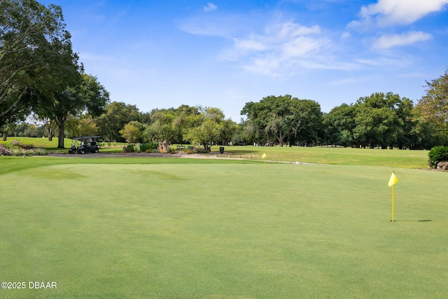view of property's community with view of golf course and a yard