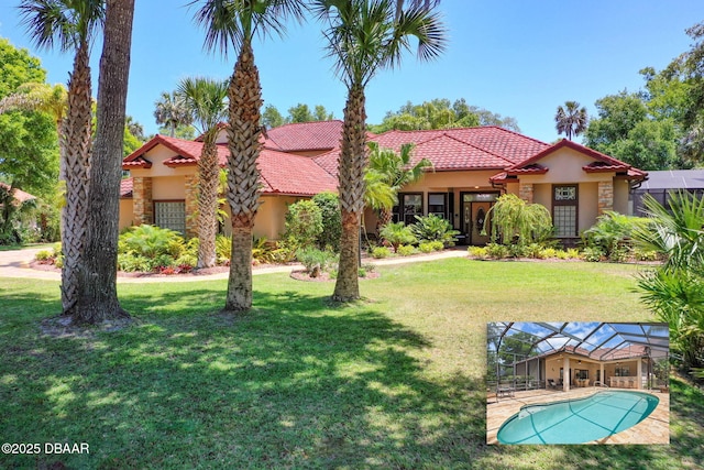 view of front of property featuring a front yard, glass enclosure, stucco siding, and a tile roof