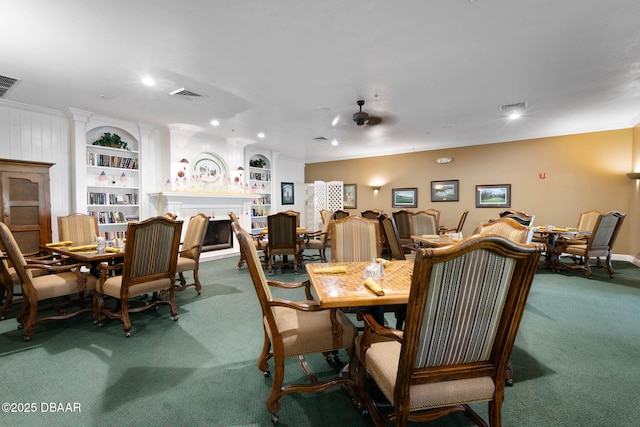 dining space with a fireplace, crown molding, carpet flooring, and visible vents