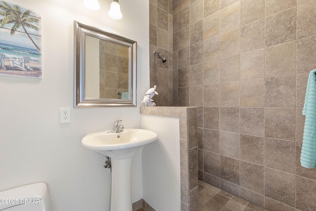 bathroom with toilet, walk in shower, and a sink