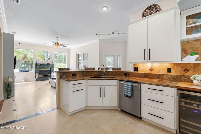 kitchen with wine cooler, stainless steel dishwasher, a sink, white cabinetry, and a peninsula