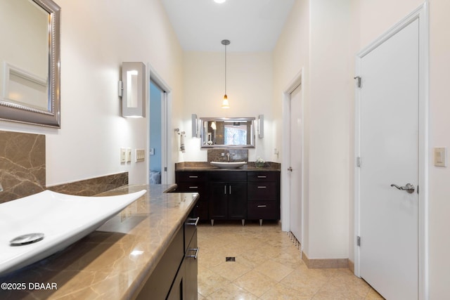bathroom featuring a sink, two vanities, tile patterned floors, baseboards, and tasteful backsplash