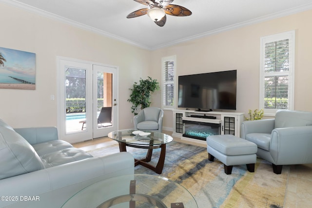 living area featuring crown molding, ceiling fan, and a glass covered fireplace