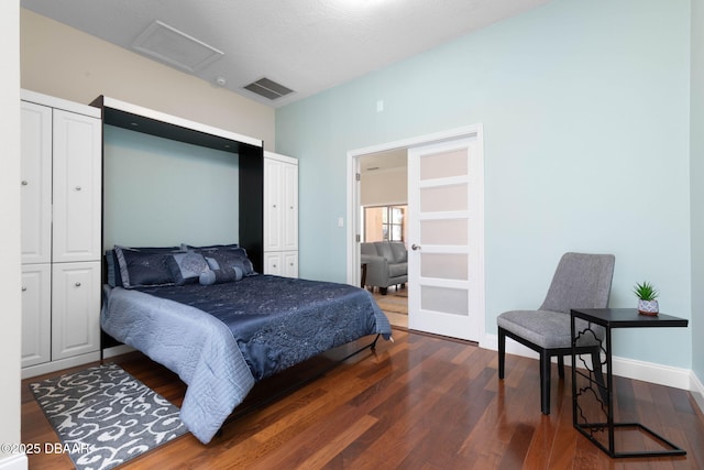 bedroom featuring baseboards, attic access, visible vents, and wood finished floors