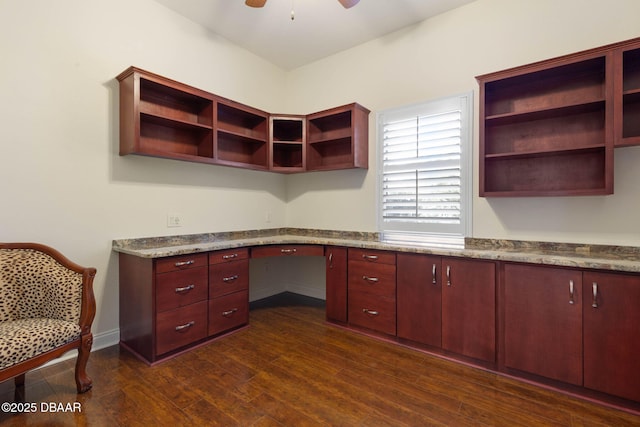 unfurnished office with built in study area, dark wood-style flooring, baseboards, and ceiling fan