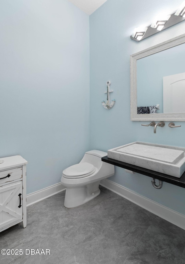 half bath featuring toilet, baseboards, and vanity