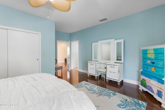 bedroom with a closet, wood finished floors, visible vents, ceiling fan, and baseboards
