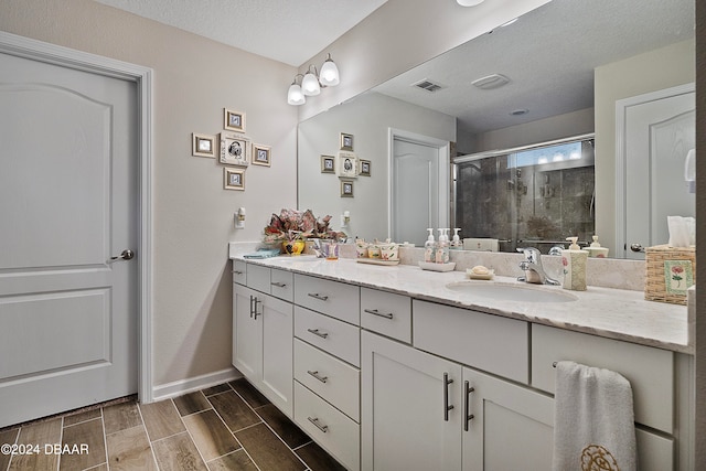 bathroom with vanity, a textured ceiling, and a shower with door