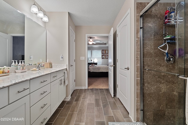 bathroom with an enclosed shower, vanity, a textured ceiling, and ceiling fan