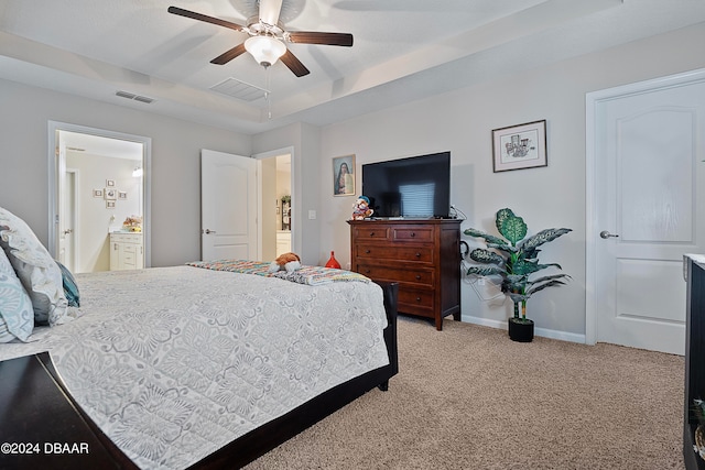 bedroom featuring light carpet, ceiling fan, and ensuite bath