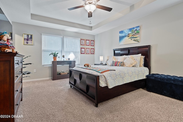 bedroom with a tray ceiling, light colored carpet, and ceiling fan