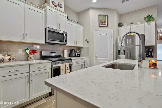 kitchen with white cabinetry, appliances with stainless steel finishes, and light stone counters